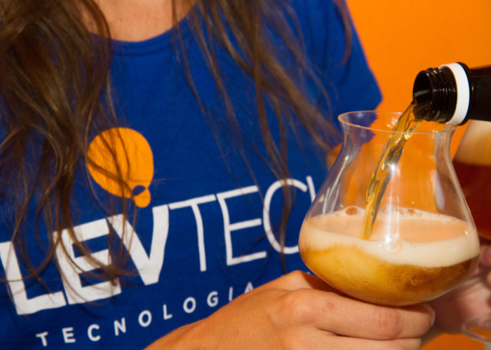 cerveja sendo servida na taça e mulher com uniforme da Levteck