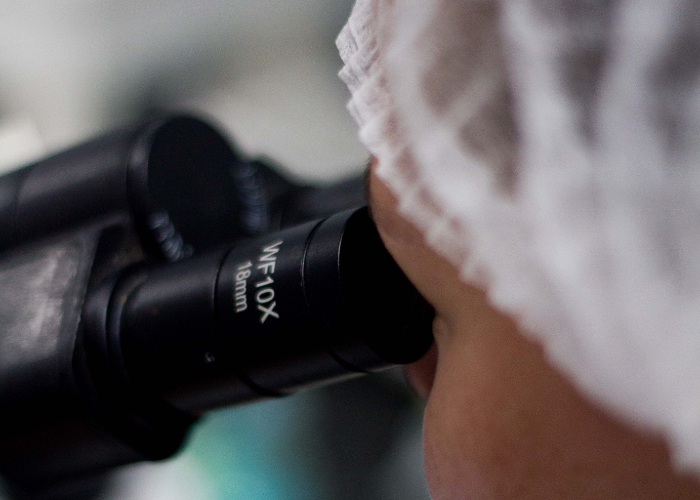 mulher olhando em um microscópio